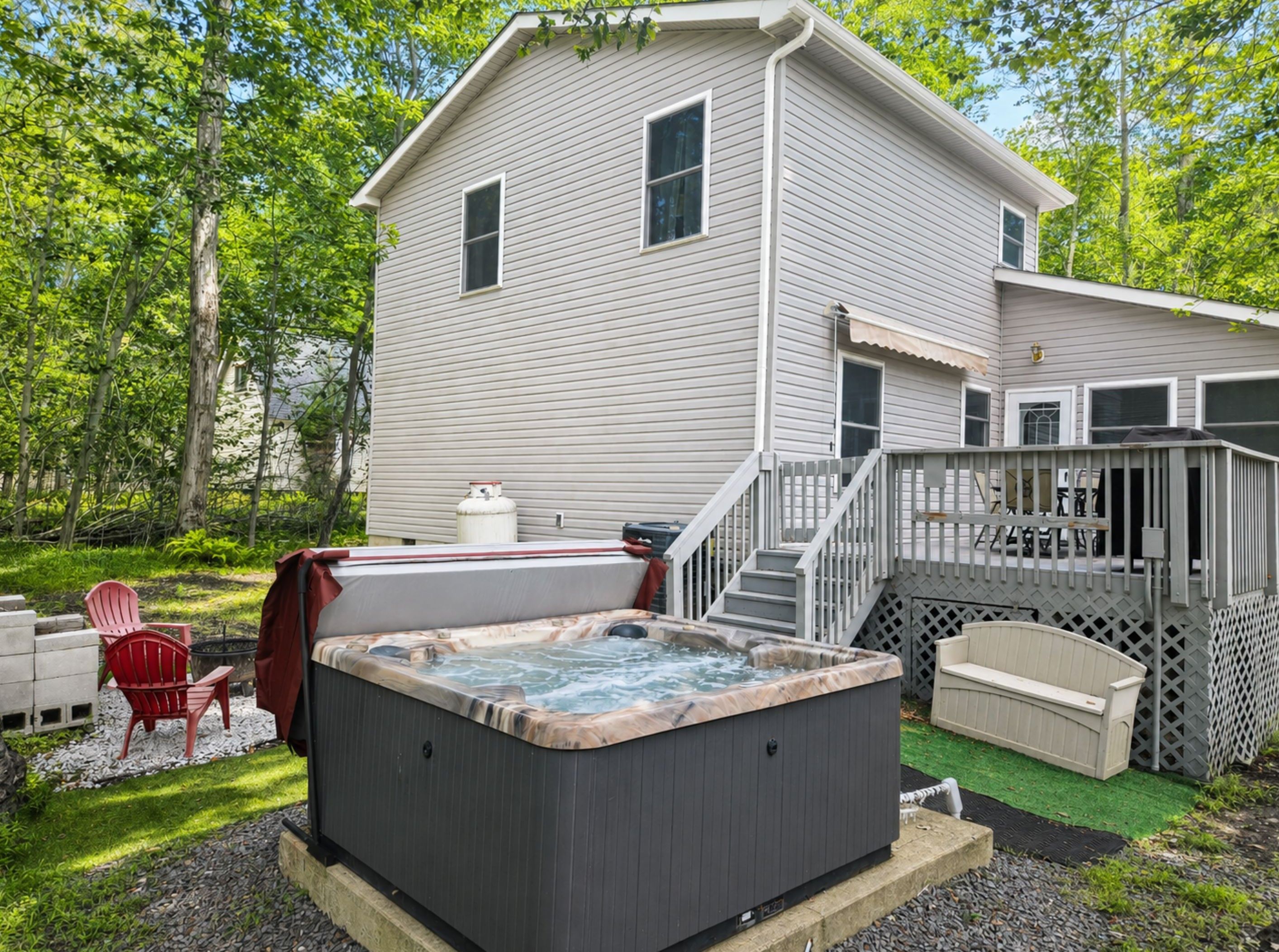 Uma casa com hidromassagem, área de estar externa e um deck.