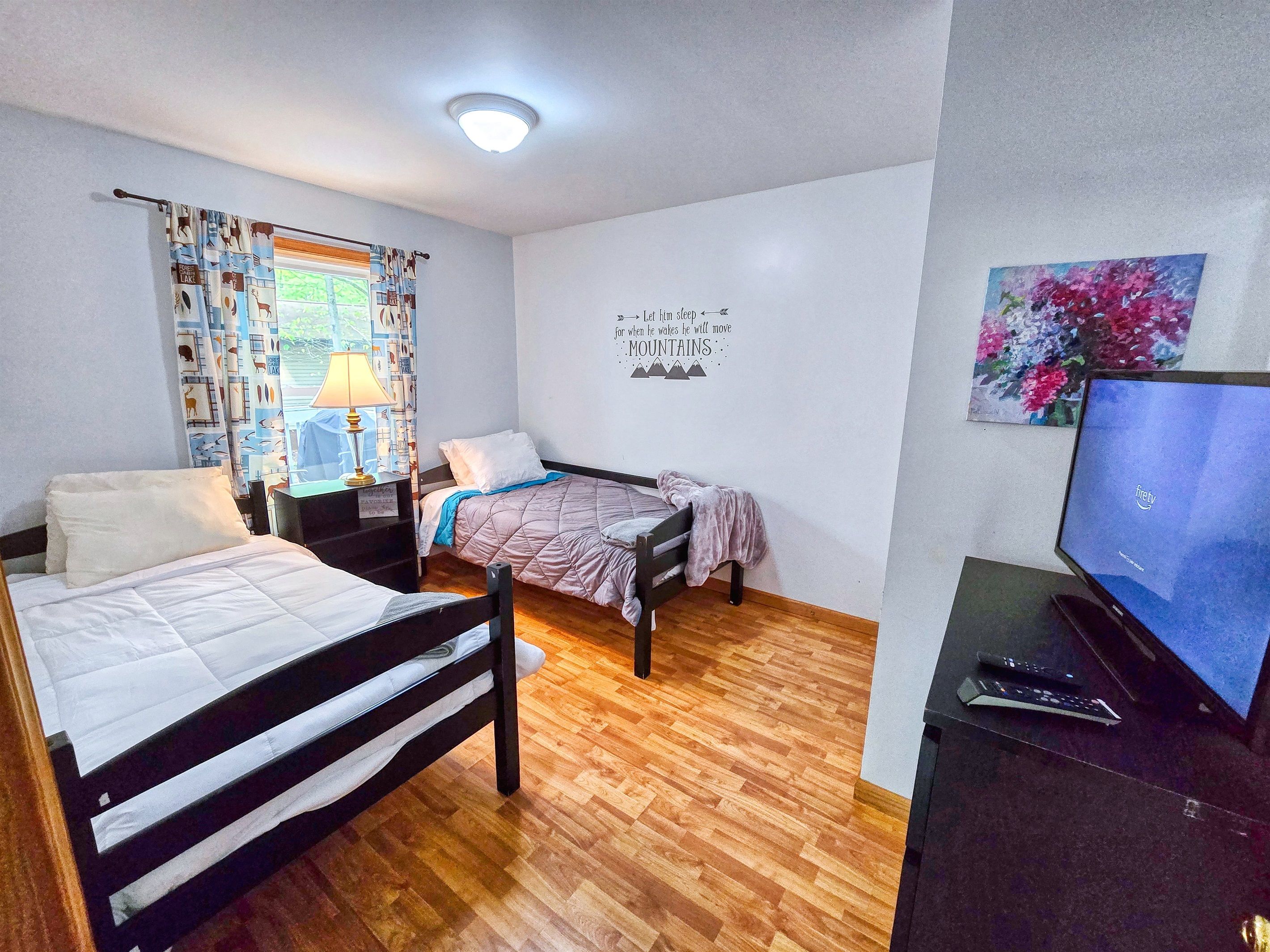 A bedroom with two beds, a desk, a TV, and a motivational quote on the wall.