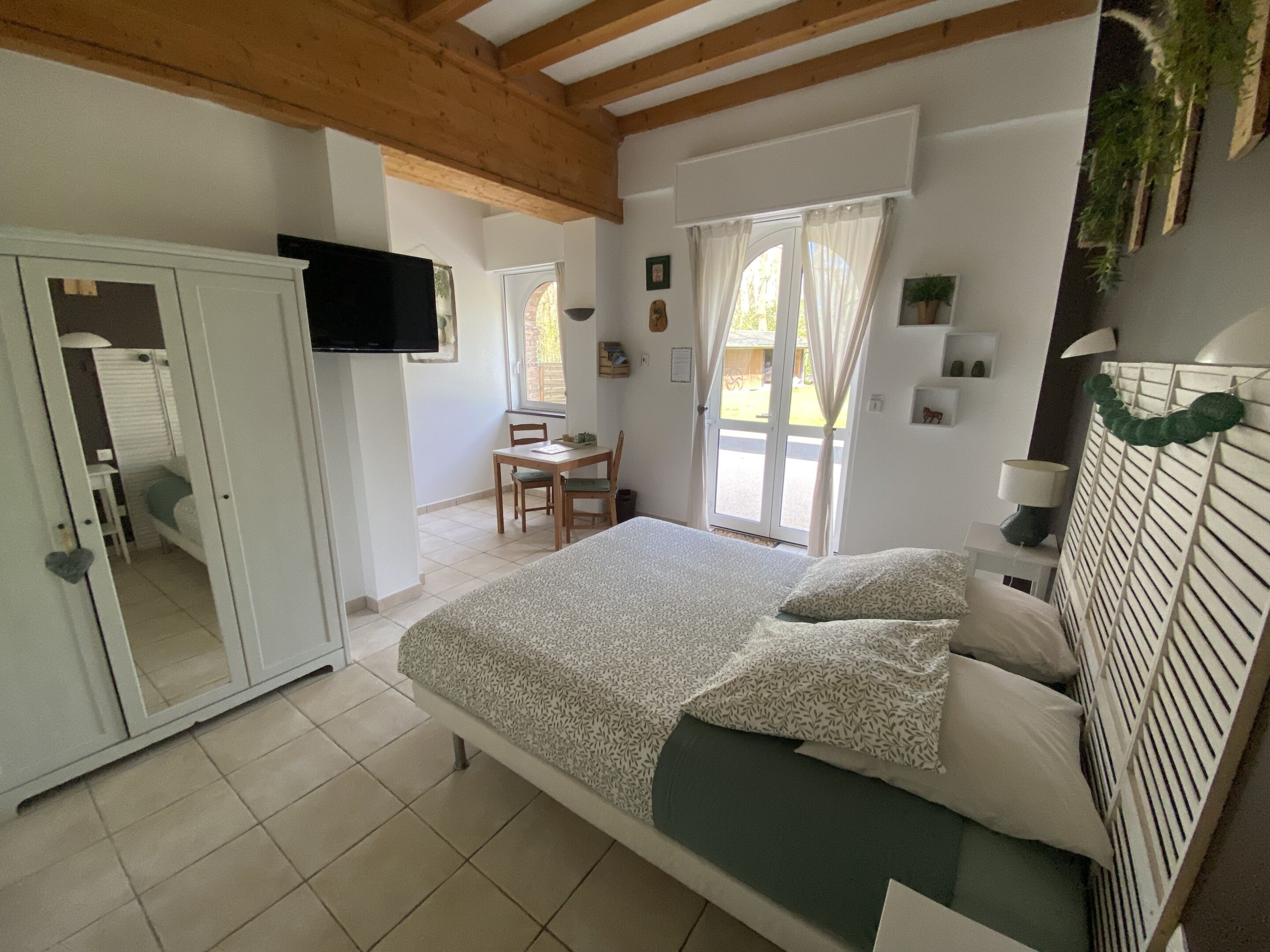 Un dormitorio con cama, televisión, escritorio y silla.