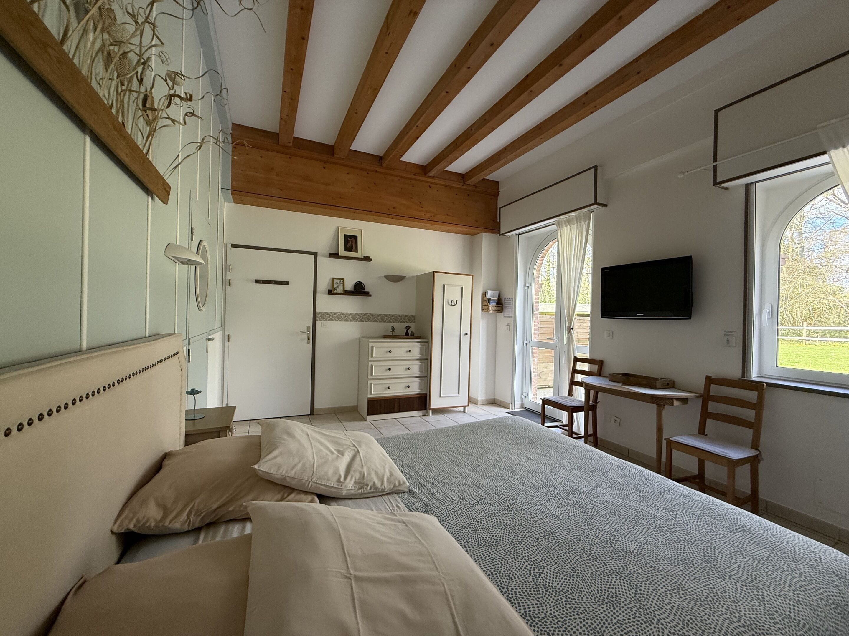 Une chambre à coucher comprenant un lit, un bureau, une chaise, une télévision et une armoire.