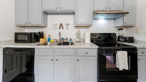 A kitchen with white cabinets, a black microwave, a stove, and a dishwasher. - Charming 3BR 2BA Retreat: Cozy! (Decatur)
