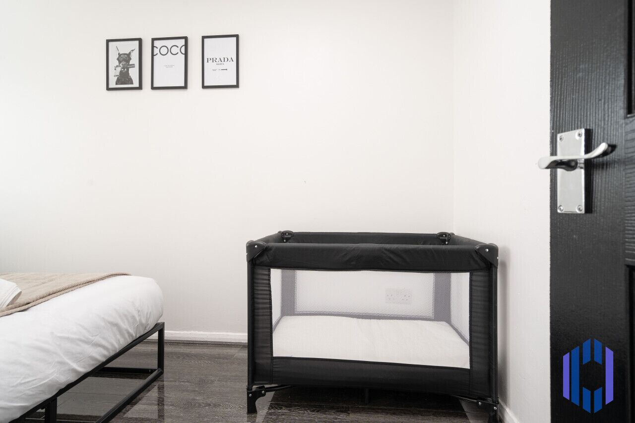 A bedroom with a bed, a small black sofa, and a door with a handle.