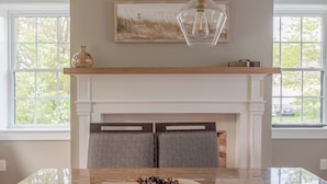A modern kitchen with a marble countertop, a bowl of pinecones, and a fireplace with a mantel above. - Historic Charm & Modern Comfort, Beach Vacation Awaits. (Wells)