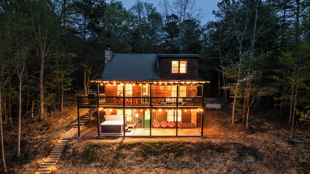 A two-story log cabin with a balcony, surrounded by a forest. - SPECIAL -  Make Your Labor Day a Mountain Getaway. Hot Tub, Fire Pit, Games (Mineral Bluff)