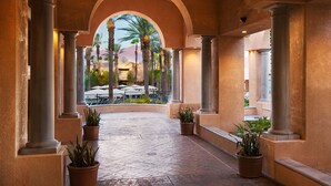 A covered walkway with columns, potted plants, and a view of outdoor seating and palm trees. - 
Palm Springs, 1BR Villa, The Westin Mission Hills Resort Villas 10/31-11/4
 (Rancho Mirage)