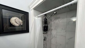 Une salle de bain avec une douche, des murs carrelés et une décoration en forme de coquillage encadré.