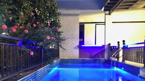 Une piscine intérieure avec un bord carrelé, une rambarde en métal et un escalier menant à un niveau supérieur.