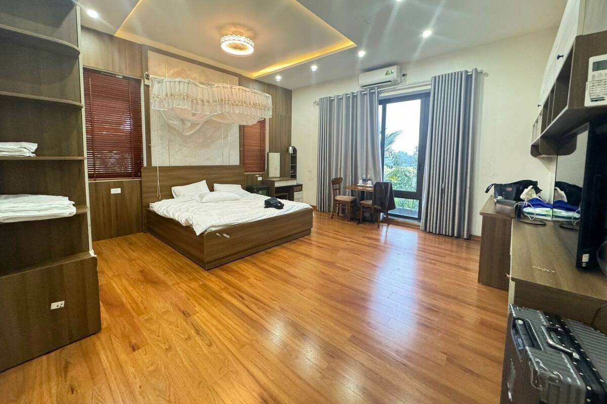 Een moderne hotelkamer met een houten vloer, een groot bed, een bureau en een kledingkast.
