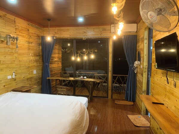 A wooden cabin room with a bed, a table, and a TV.