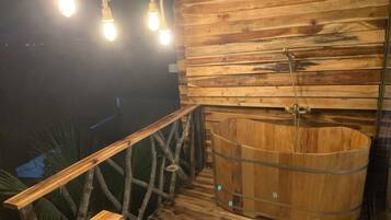 A wooden deck with a hot tub and a bench.