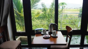 Una habitación con una mesa dispuesta para dos personas, un hervidor, tazas y una caja de pañuelos.