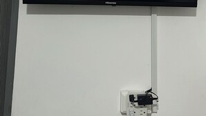Un téléviseur à écran plat fixé au mur, branché à une prise de courant.