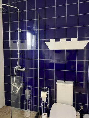 A bathroom with a shower, toilet, and a towel rack.