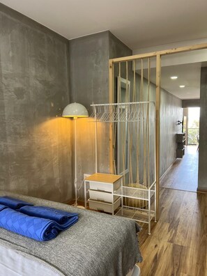 A modern room with a bed, a hanging rack, and a lamp.