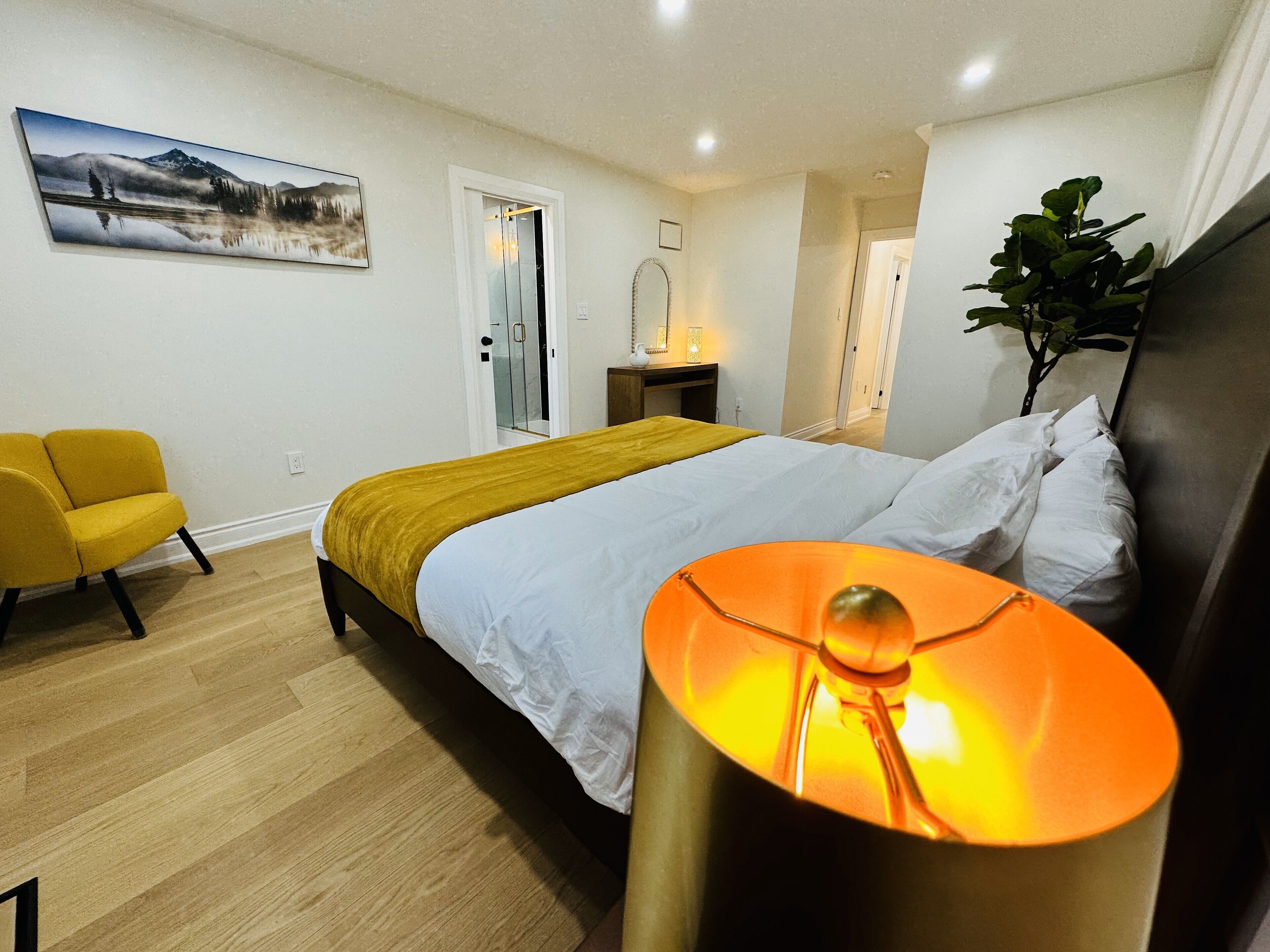 A modern bedroom with a bed, a yellow armchair, a bedside table, and a large window.