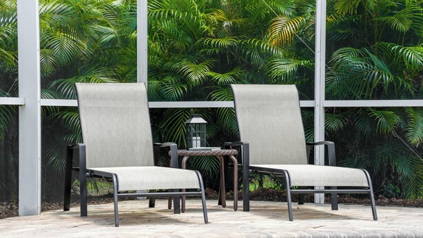 Two lounge chairs with metal frames and grey fabric seats, positioned near a pool with a tiled edge. - Lake Front! Spacious Home w/heated pool & kayaks (Lake Wales)