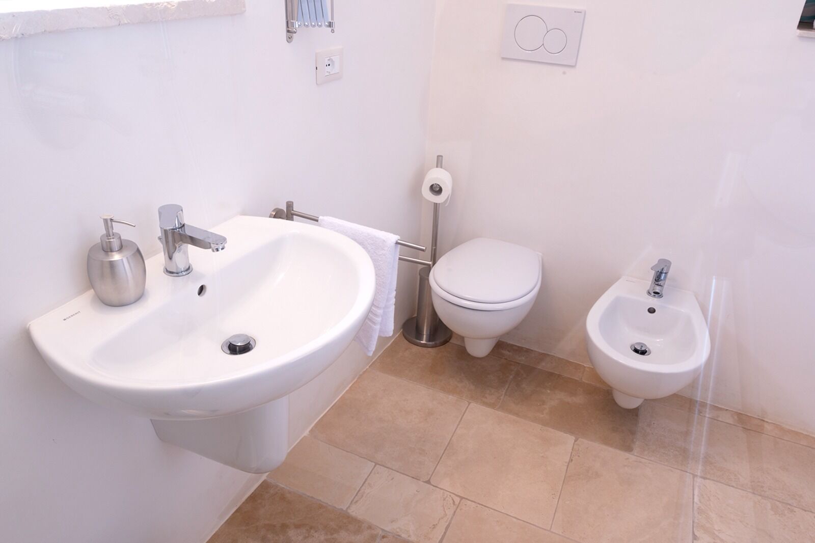 A bathroom with a large sink, toilet, and bidet.