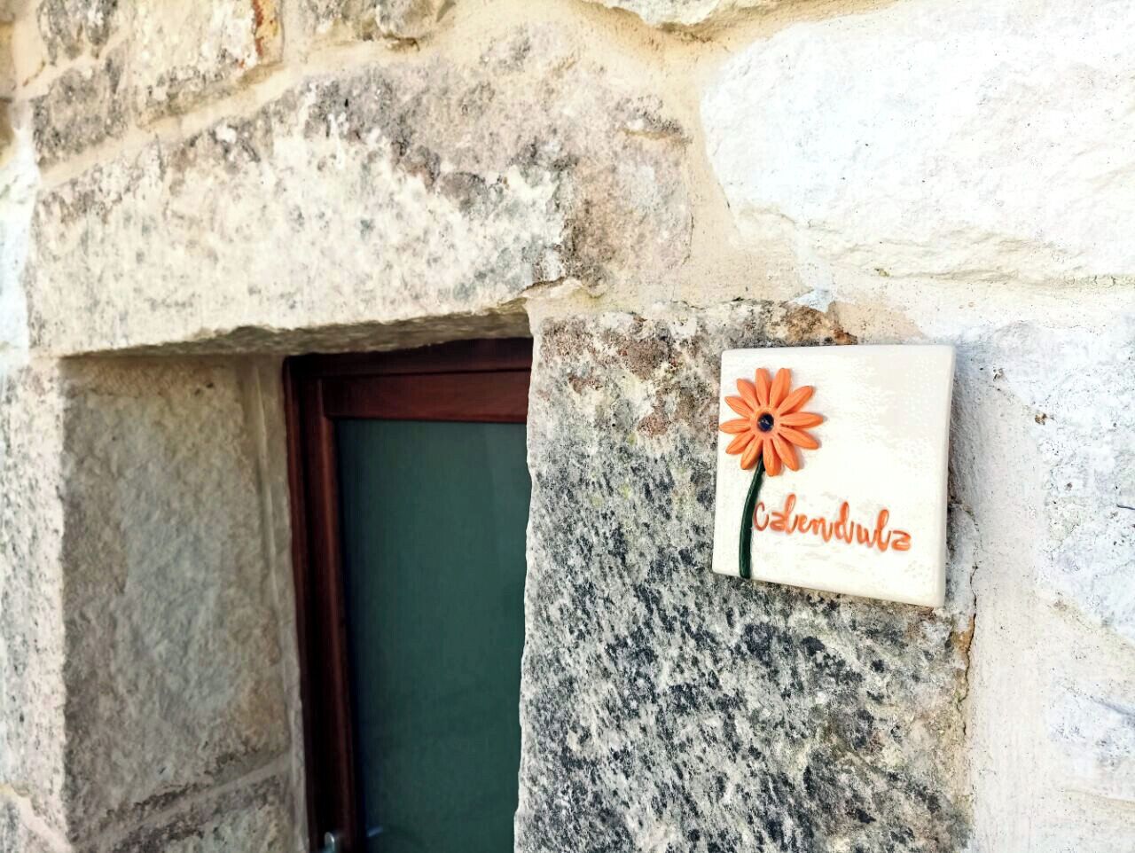 Un muro di pietra con una porta e un cartello con su scritto 'induluz'.