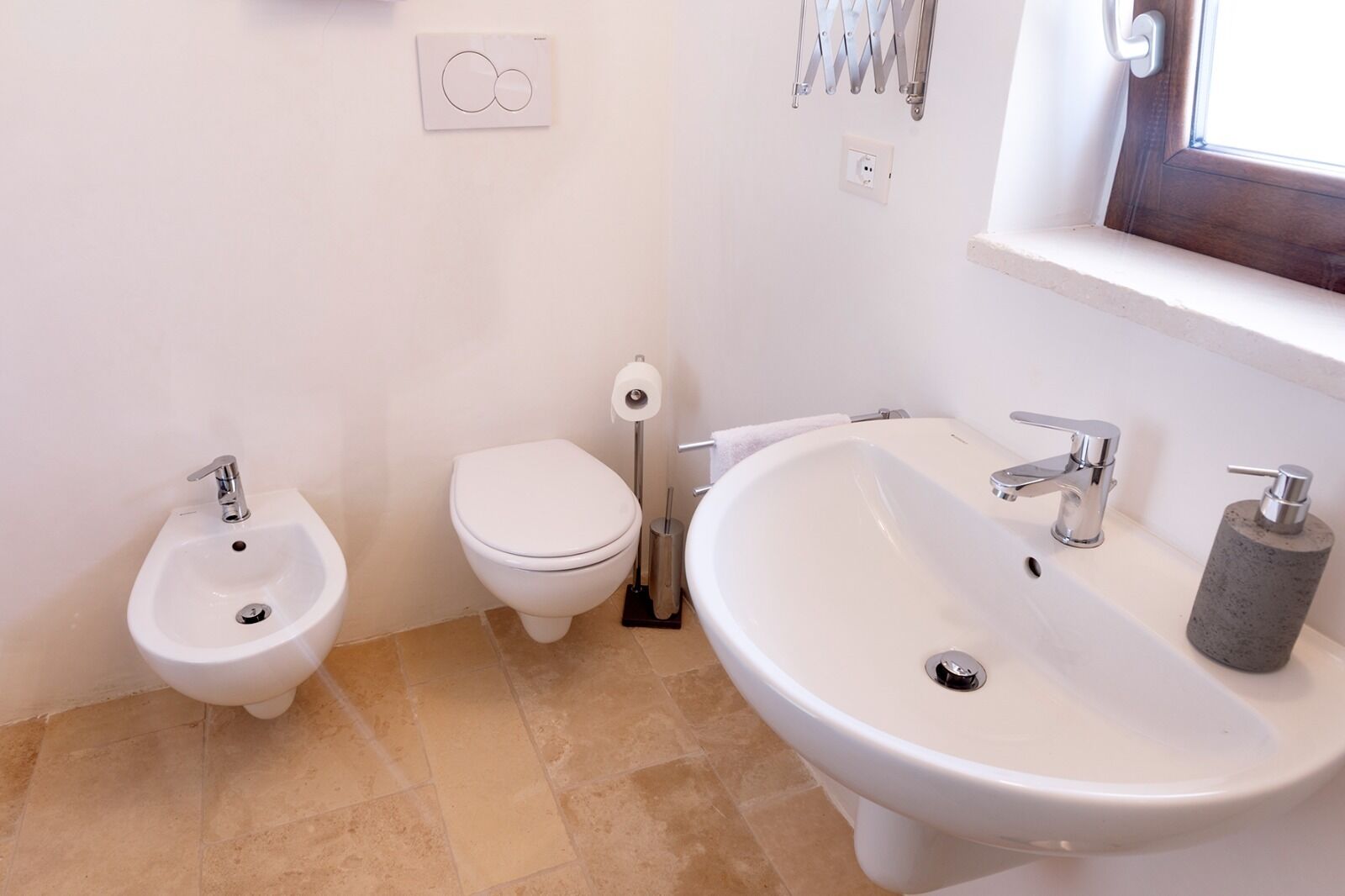 Un bagno con bidet, toilette e lavabo.