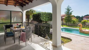 A covered patio with a dining table, chairs, and a swimming pool with a swan float. - Romantic villa with istrian tavern (Labin)