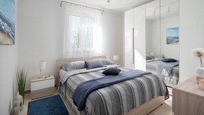 A modern bedroom with a large bed, bedside tables, a mirror, and a view of the outdoors through a window. - Romantic villa with istrian tavern (Labin)