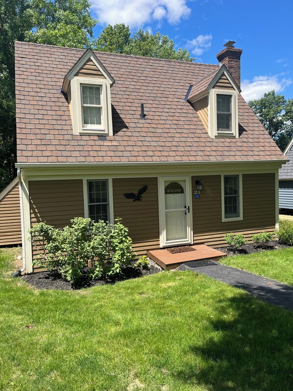 A two-story house with a brown roof, a chimney, and a front porch. - Welcome to Serenity Cottage! (Galena)