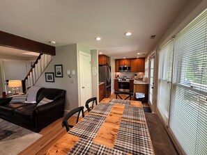 A modern kitchen with wooden cabinets, stainless steel appliances, and a dining area with a checkered table runner. - Welcome to Serenity Cottage! (Galena)