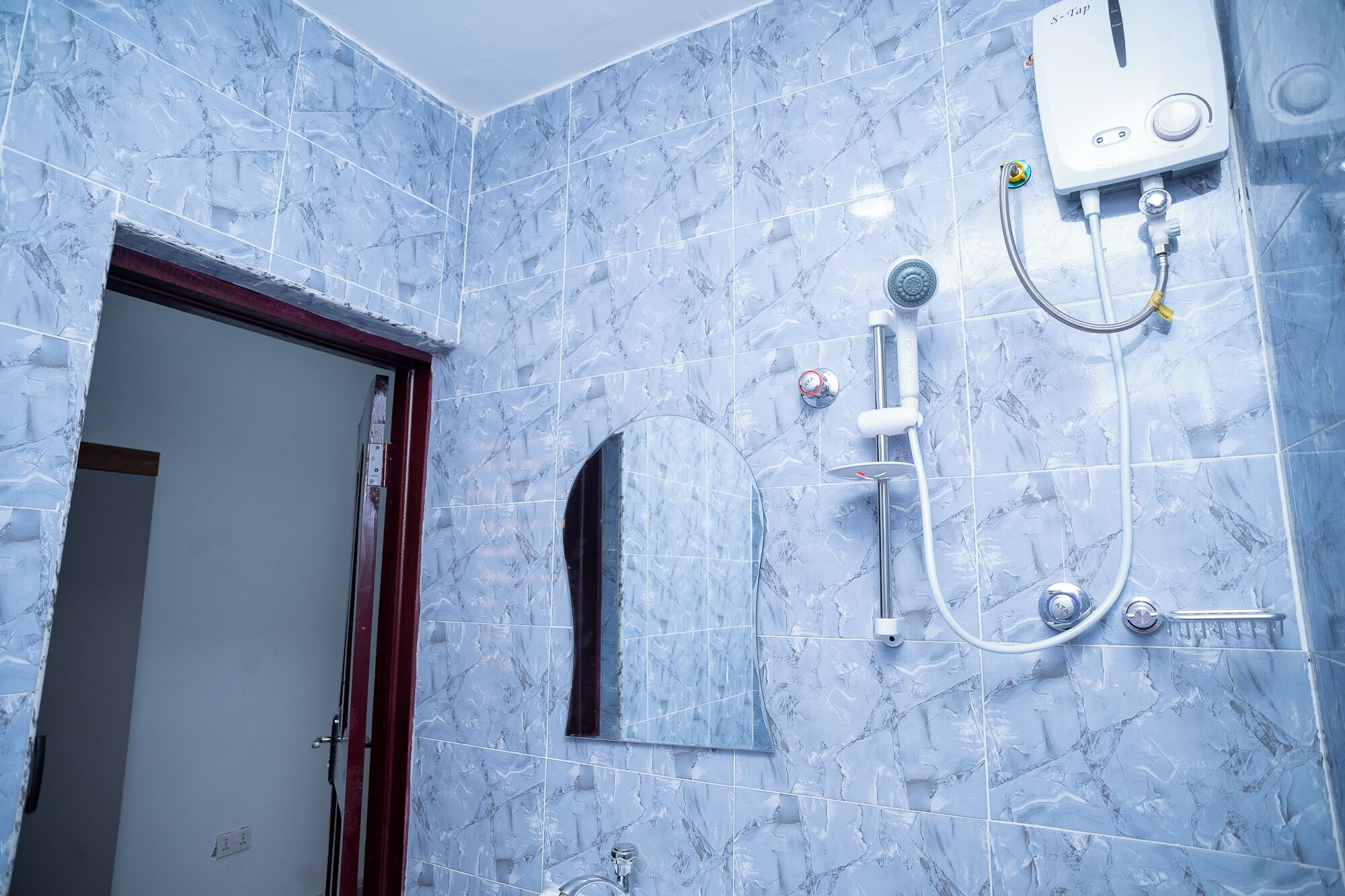 Une salle de bain avec une douche, un miroir et un porte-serviettes.
