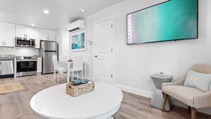 A modern kitchen with white cabinetry, stainless steel appliances, and a dining area with a round table.