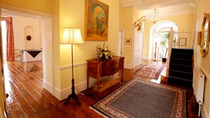 A hallway with wooden flooring, a lamp, a painting, a staircase, and a radiator. - Chelsea Parkfields  (Ross-on-Wye)