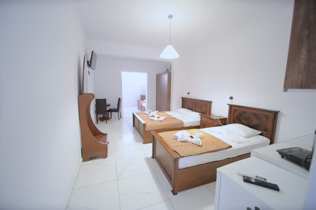 A hotel room with two beds, a desk, a chair, a TV, and a wardrobe.