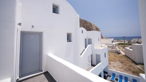 Un edificio blanco con una puerta que dice '8', una escalera y vista al mar.