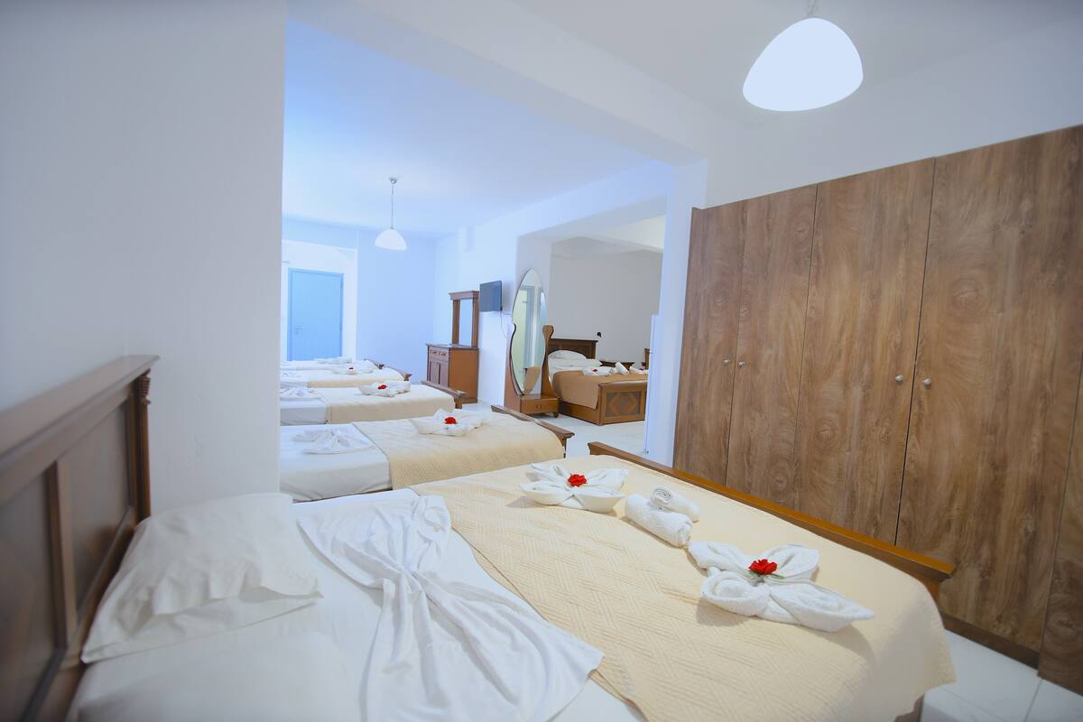 A hotel room with two beds, wooden wardrobe, and a large mirror.