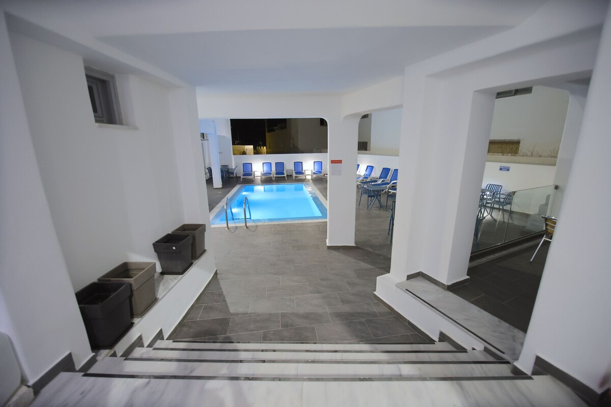 L’intérieur d’un hôtel avec un espace piscine, un escalier et des sièges disposés près de la piscine.