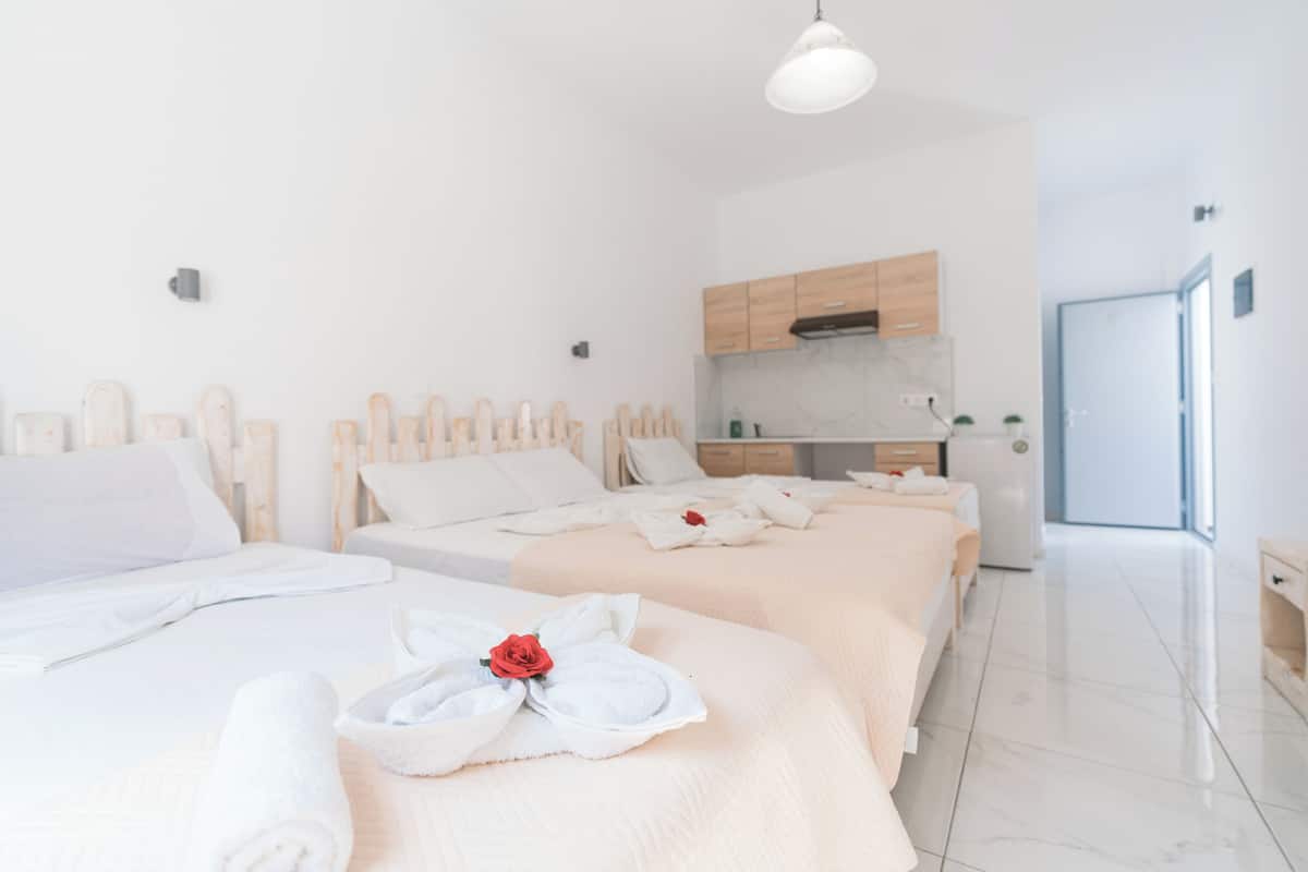 A hotel room with two beds, a kitchenette, and a bathroom.