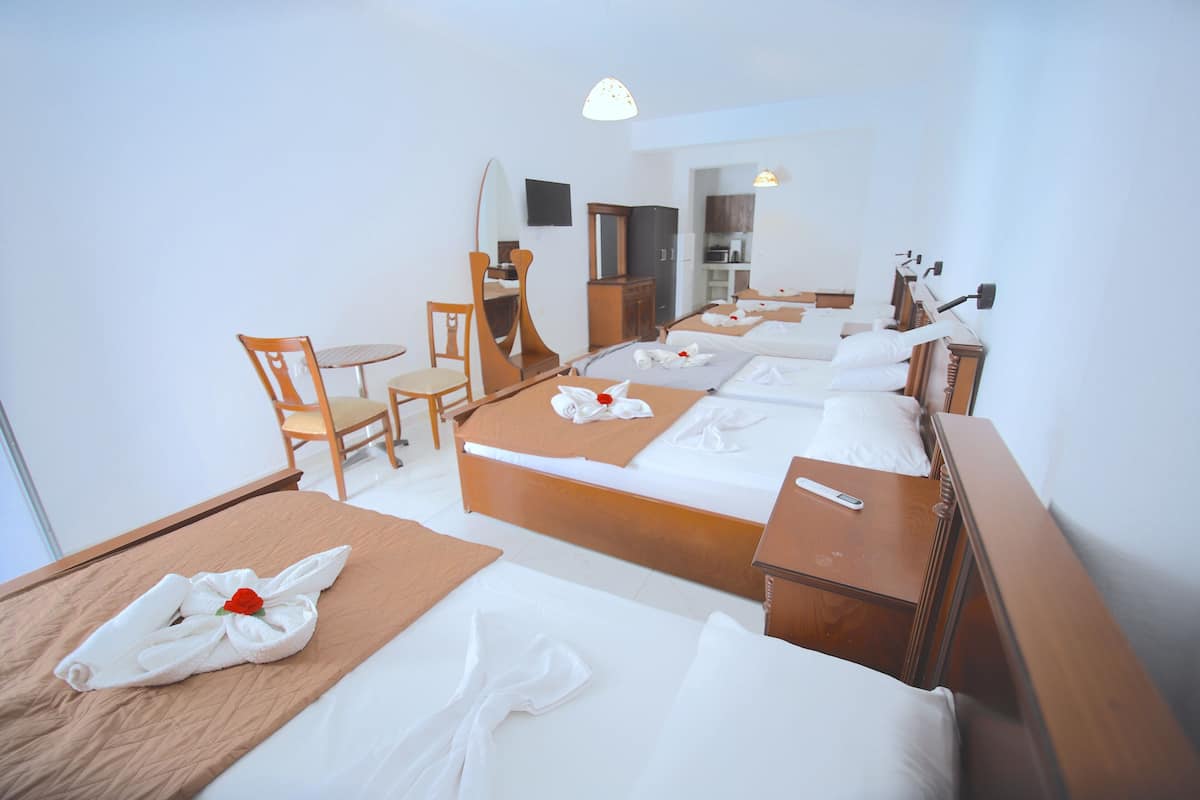 A hotel room with two beds, a desk, a chair, a mirror, and a television.