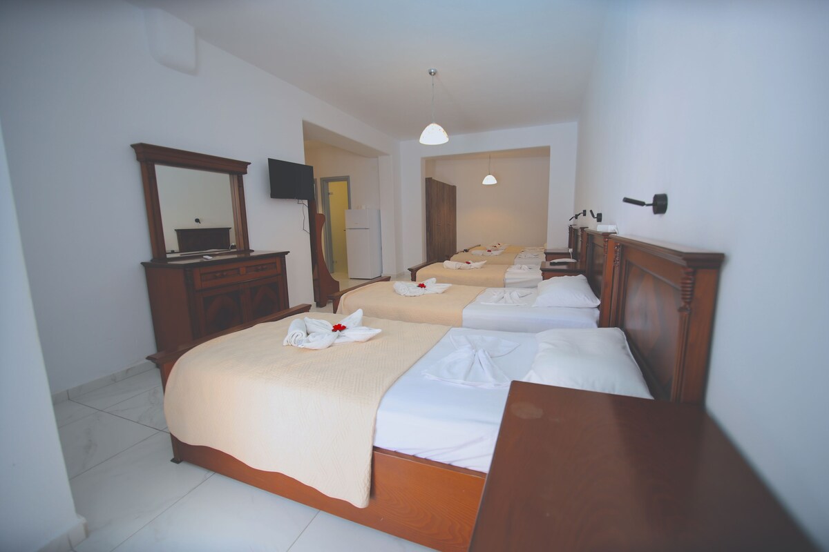 A hotel room with two beds, a wooden dresser, a mirror, a television, and a door leading to another room.