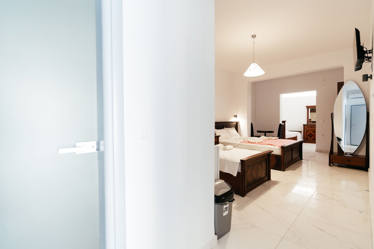 A hotel room with two beds, a large mirror, a ceiling light, and a trash bin.