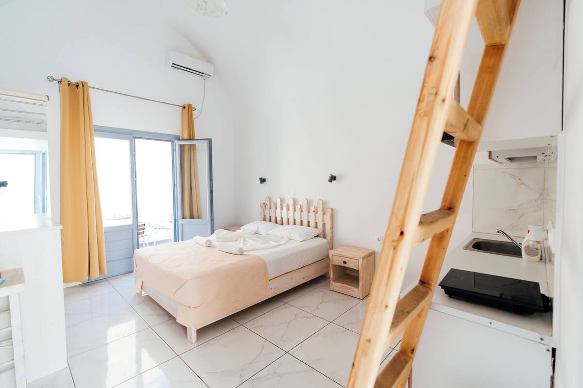 A modern bedroom with a bed, bedside table, and a wooden ladder.