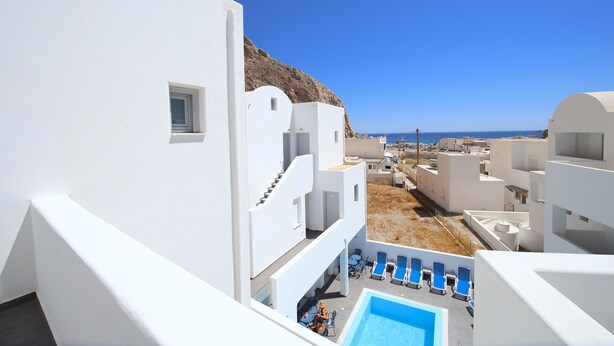 Un edificio blanco con piscina y sillones de descanso.