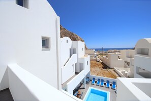 Un edificio blanco con piscina y sillones de descanso.