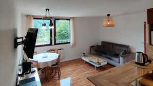 A compact living space with a dining area, a sofa, and a kitchen counter.