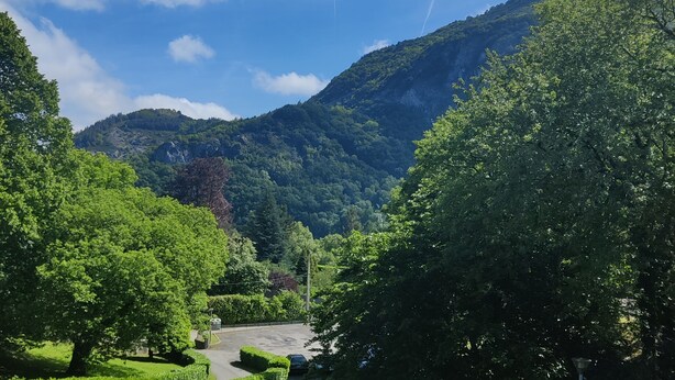A lush green landscape with a clear sky, a mountain in the background, and a road leading into the distance.