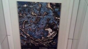Uma casa de banho com uma obra de arte emoldurada sobre o autoclismo.