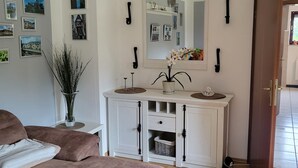 Un salon avec un canapé, une console blanche agrémentée d’un miroir et un plancher en bois.