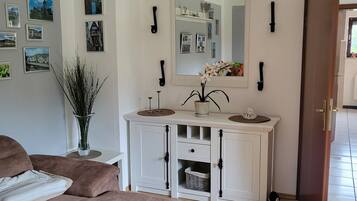 Un salon avec un canapé, une console blanche agrémentée d’un miroir et un plancher en bois.