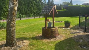 Un cadre extérieur rustique agrémenté d’un grand arbre, d’une petite construction en bois et d’une pelouse bien entretenue.