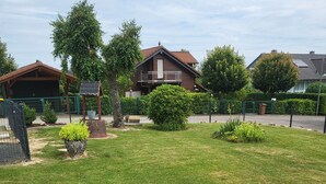Un jardin bien entretenu, avec un foyer circulaire en pierre, entouré d’une bordure basse également en pierre.