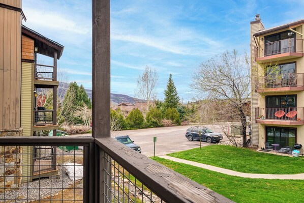 Enjoy the view from this building's balcony overlooking the street and surrounding greenery.