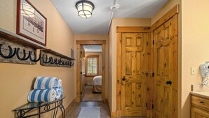 Un pasillo con puertas de madera, un perchero de toallas en la pared, un cuadro enmarcado y una mesita con toallas.